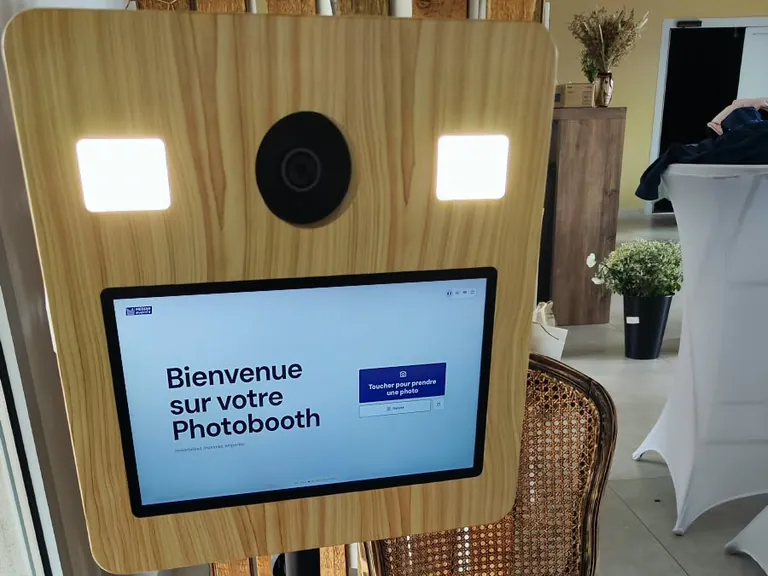 Borne photobooth sur trépied à côté d’une chaise cannée de style ancien